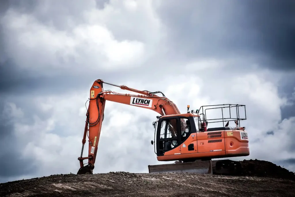 Escavadeira Llynch em operação em um terreno com céu nublado, destacando equipamentos essenciais para a mobilidade e resistência na indústria de processos pesados.