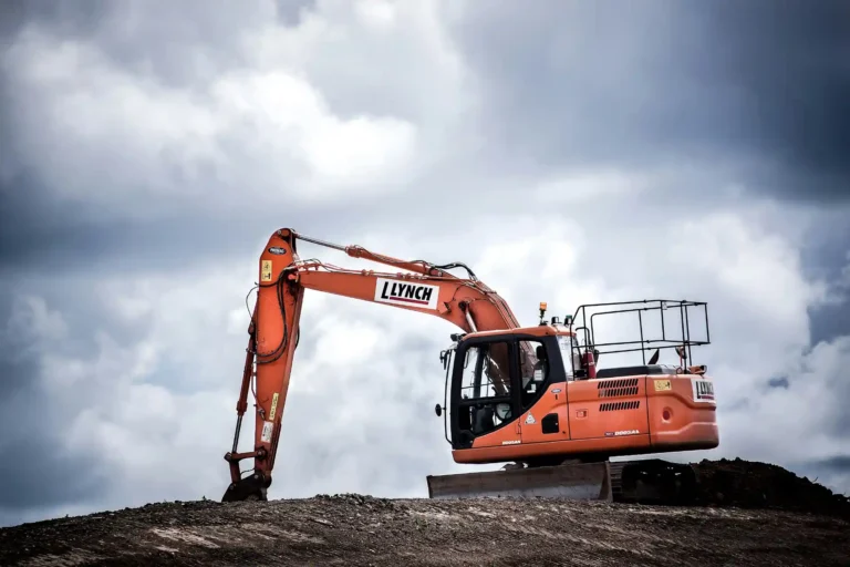 Escavadeira Llynch em operação em um terreno com céu nublado, destacando equipamentos essenciais para a mobilidade e resistência na indústria de processos pesados.