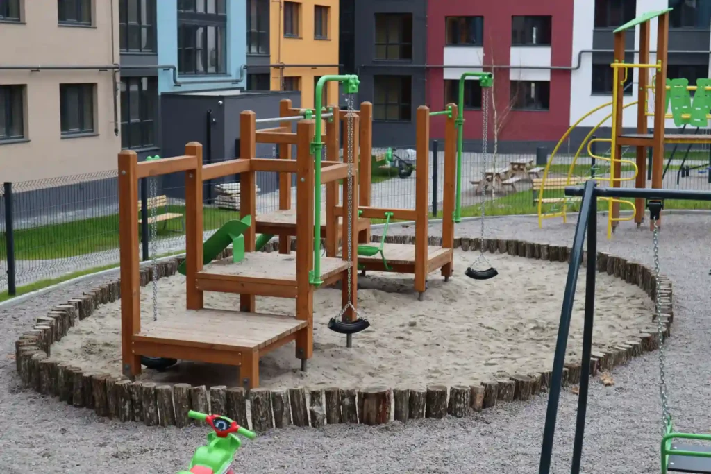 Playground inovador com estruturas de madeira e área de brincar com areia, ideal para estimular o desenvolvimento infantil e criar espaços de diversão criativos