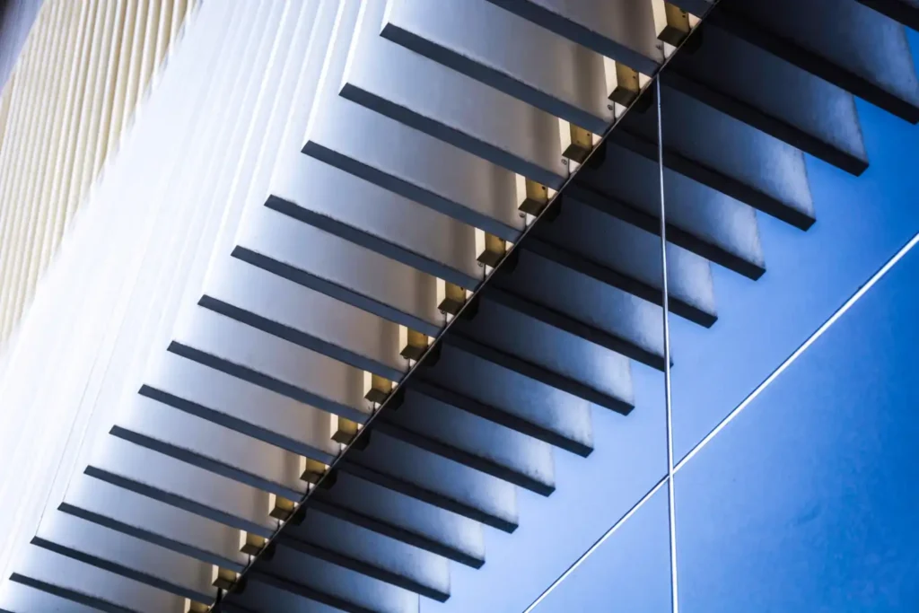 Detalhes de uma escada moderna com degraus de alumínio e aço, valorizando a decoração contemporânea de ambientes sofisticados.