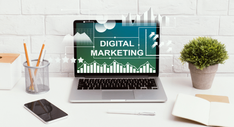 Laptop sobre mesa de trabalho exibindo “Digital Marketing” na tela com gráficos e indicadores de desempenho.