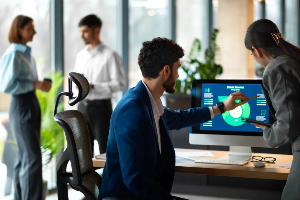 Trabalhadores em escritório usando tecnologia em telas com dashboards de automação, enquanto uma pessoa interage com um sistema digital para apoiar a Automação de Processos: Como a Tecnologia Pode Aumentar a Produtividade Das Empresas